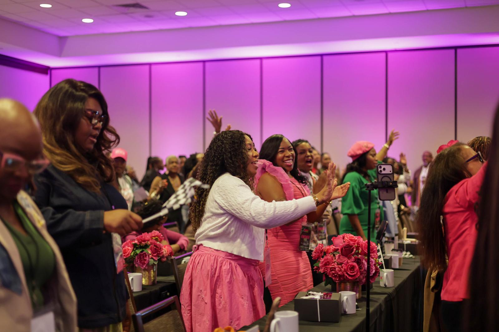 Women gathered around tables with hands lifted